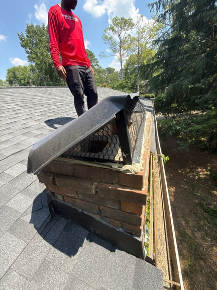 Shelter Guard technician inspecting a chimney chase cap for rust and seam damage