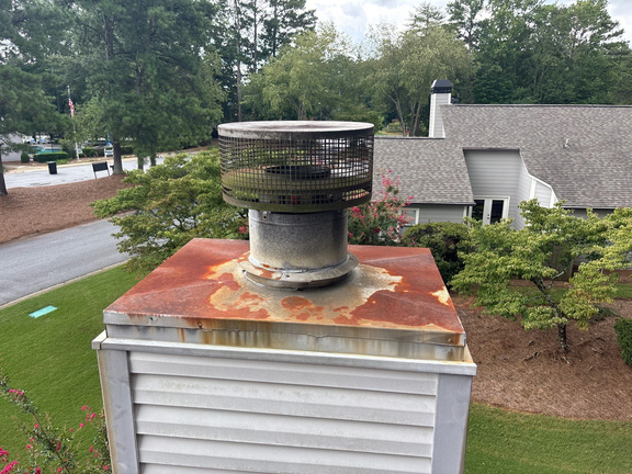 Close-up of heavy rust streaking on a metal chimney chase cap