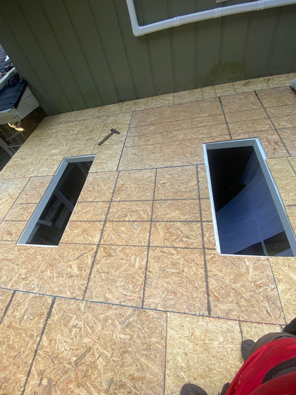 Two skylight openings cut into a fresh OSB roof deck before the units go in