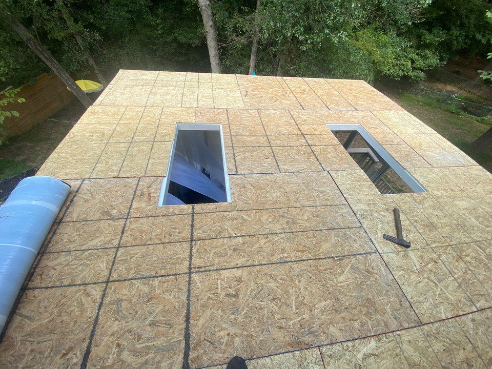 Flat roof deck opened up with two skylight rough openings cut and ready for new curbs
