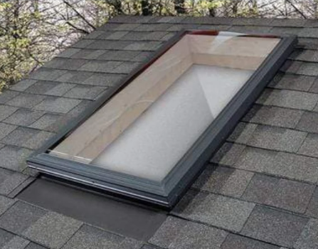 New skylight with dark metal flashing set into gray architectural shingles
