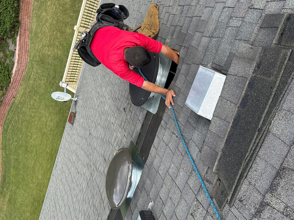 Shelter Guard technician sealing the flange of a new dome attic fan into the shingles