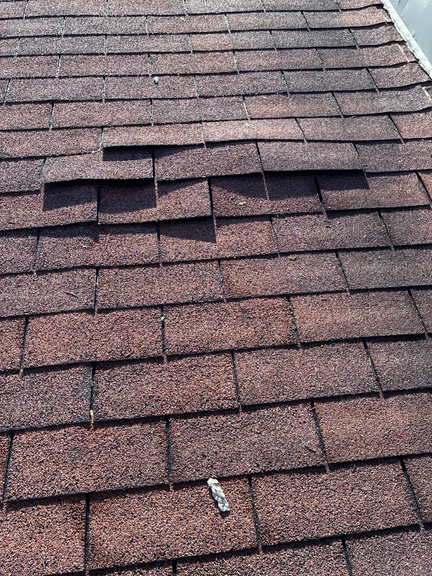 Close-up of a missing and curling asphalt shingle on a Marietta roof