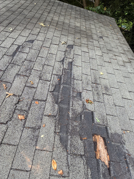 Close-up of a damaged asphalt shingle roof section in Marietta showing wear near a valley