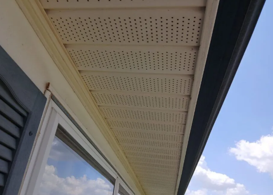 Continuous soffit vent strip running under a roof overhang against a blue sky