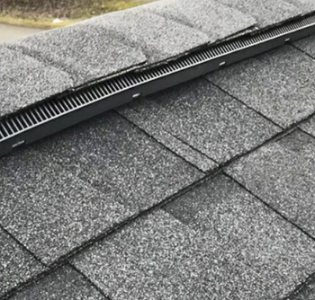 Ridge vent meeting white gable trim at the peak of a shingle roof