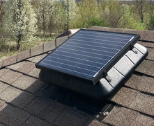 Solar attic fan viewed from the side on a shingle roof