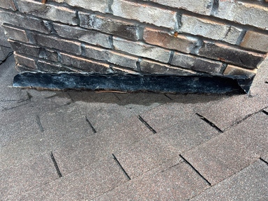 Weathered roof flashing meeting a brick chimney