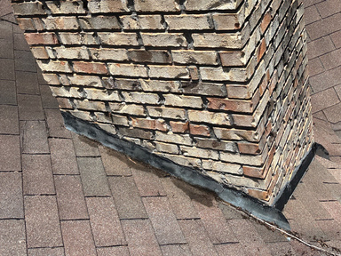 Close-up of chimney corner flashing detail on a shingle roof