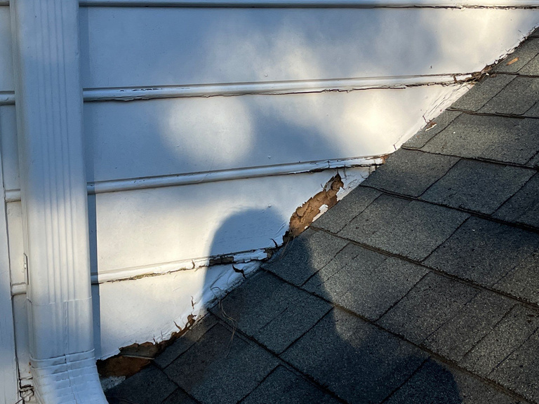 Warped and cracked siding panel on the side of a house