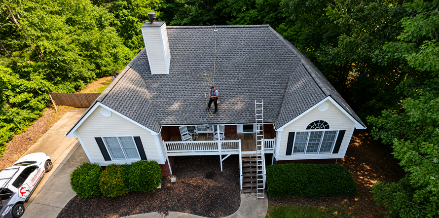 Aerial view of technician inspecting a roofline from above