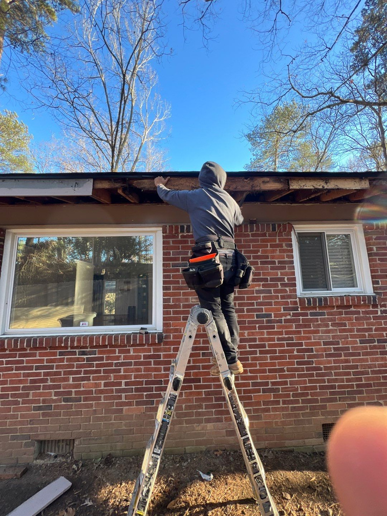 Technician inspecting rotted wood at a roofline