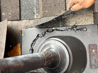 Technician replacing a pipe boot on a shingle roof