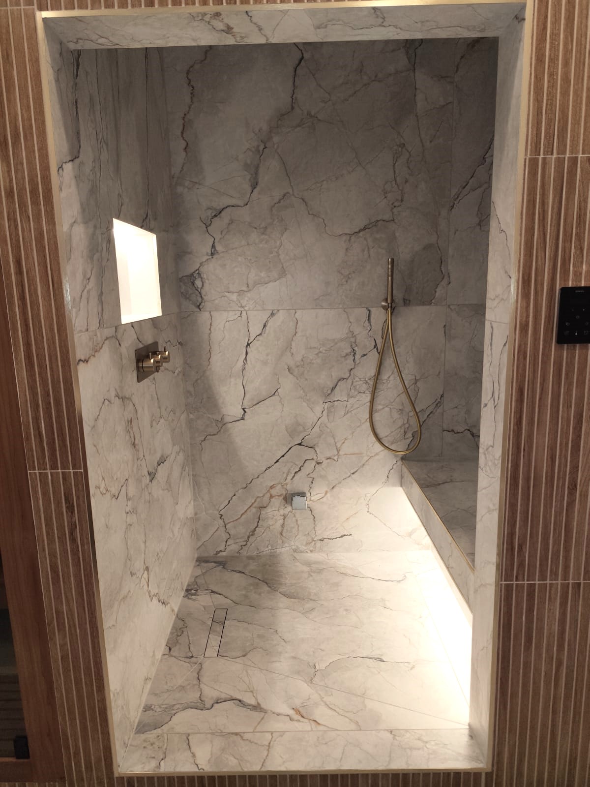 Small shower bathroom with layered mirror lighting and a warm neutral feel