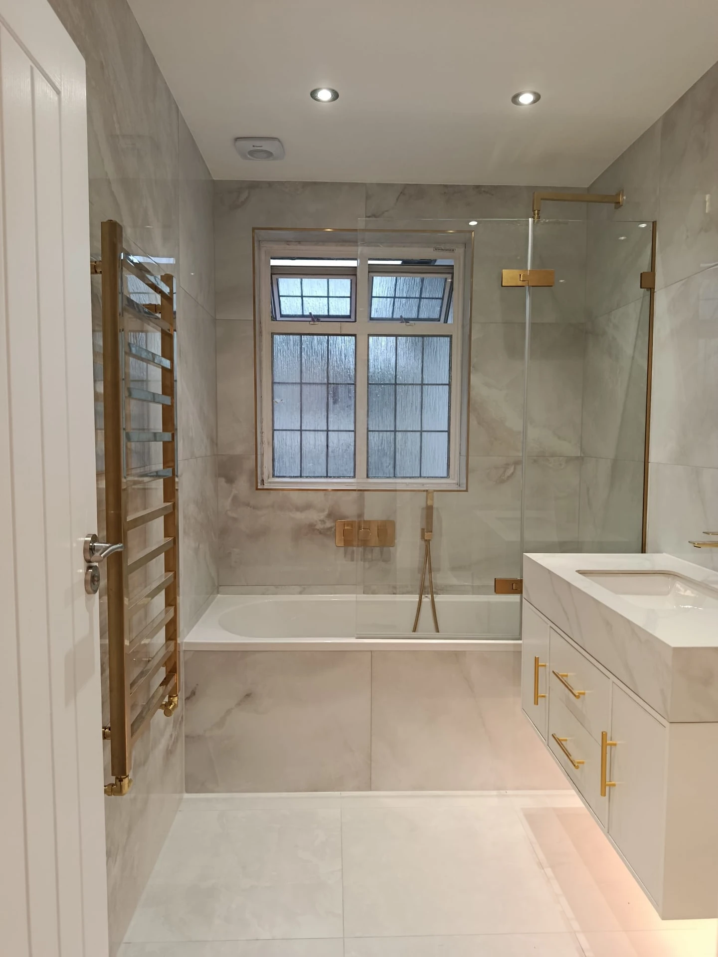 Small bathroom with calm neutral tiles, limited material changes and a clean finish palette for a more open look
