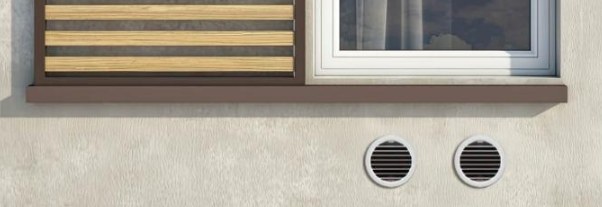 Deux grilles d'aération rondes sous une fenêtre, seule trace d'un climatiseur monobloc en façade