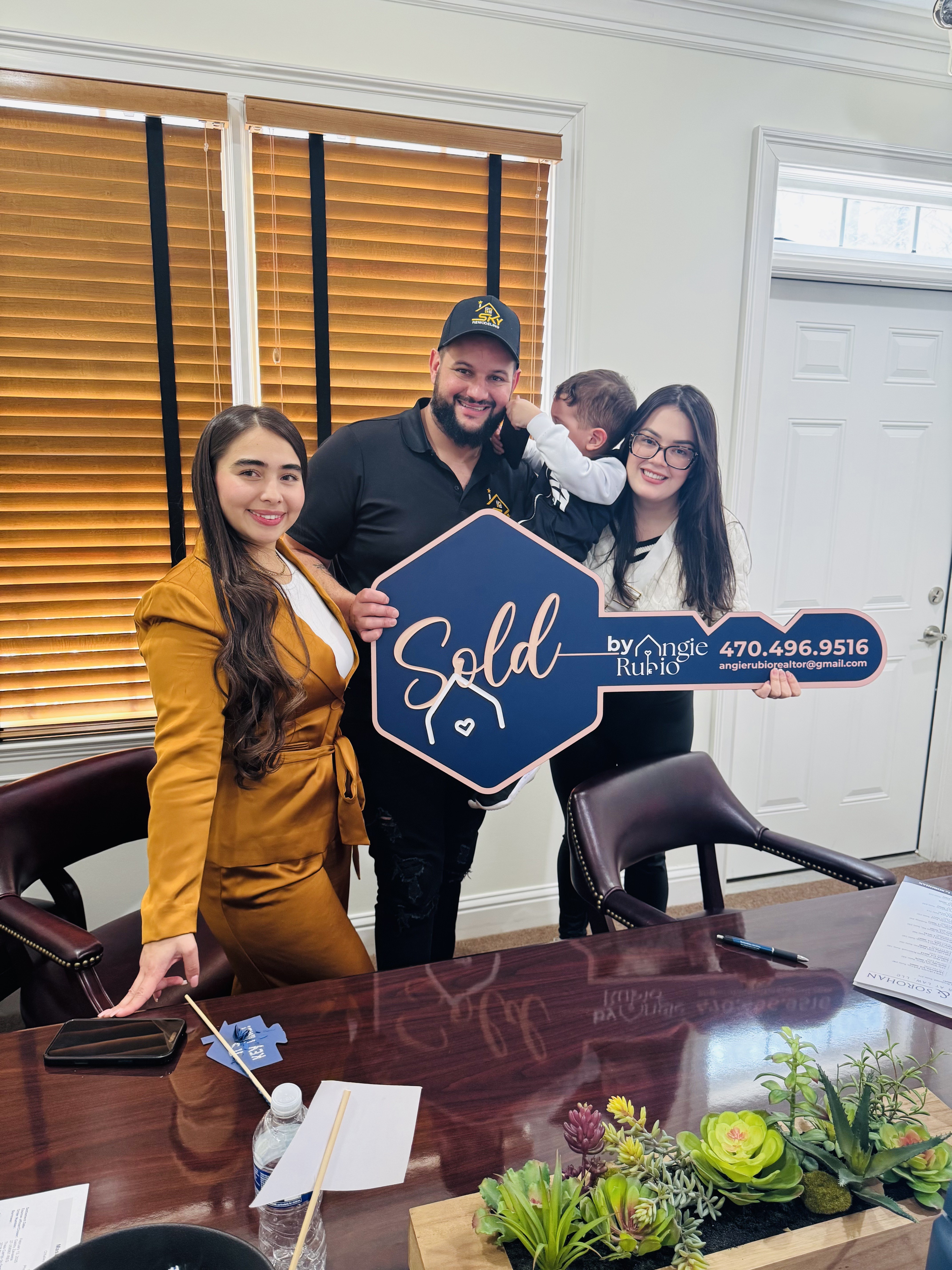 Familia posando con el letrero de venta despu&eacute;s de cerrar su compra en Georgia