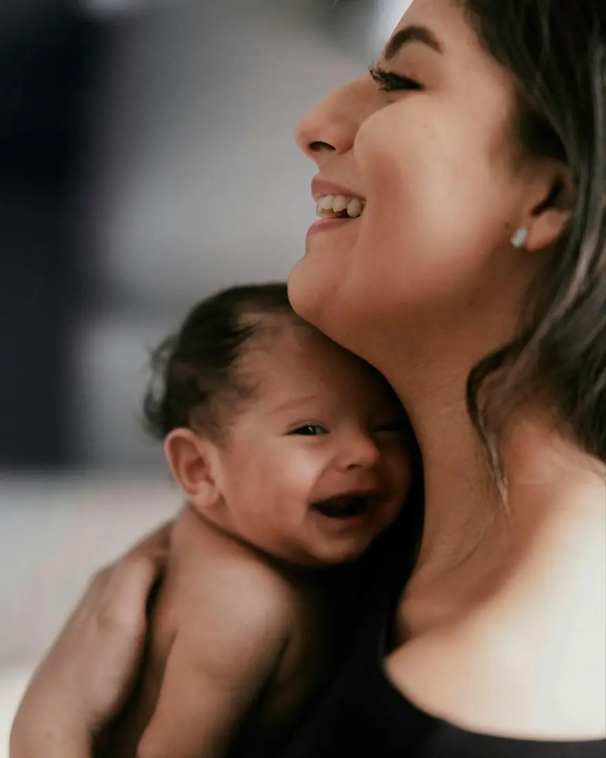 A mother smiles as she holds her baby