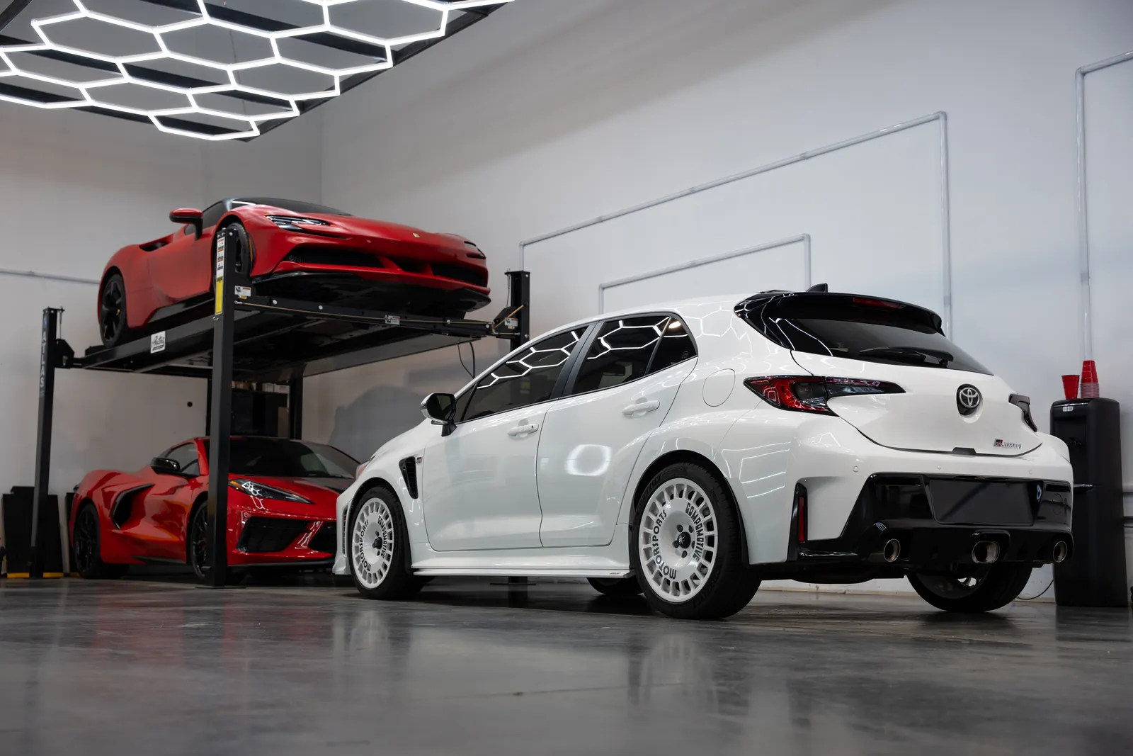Storage lifts with a red sports car and a white hatchback