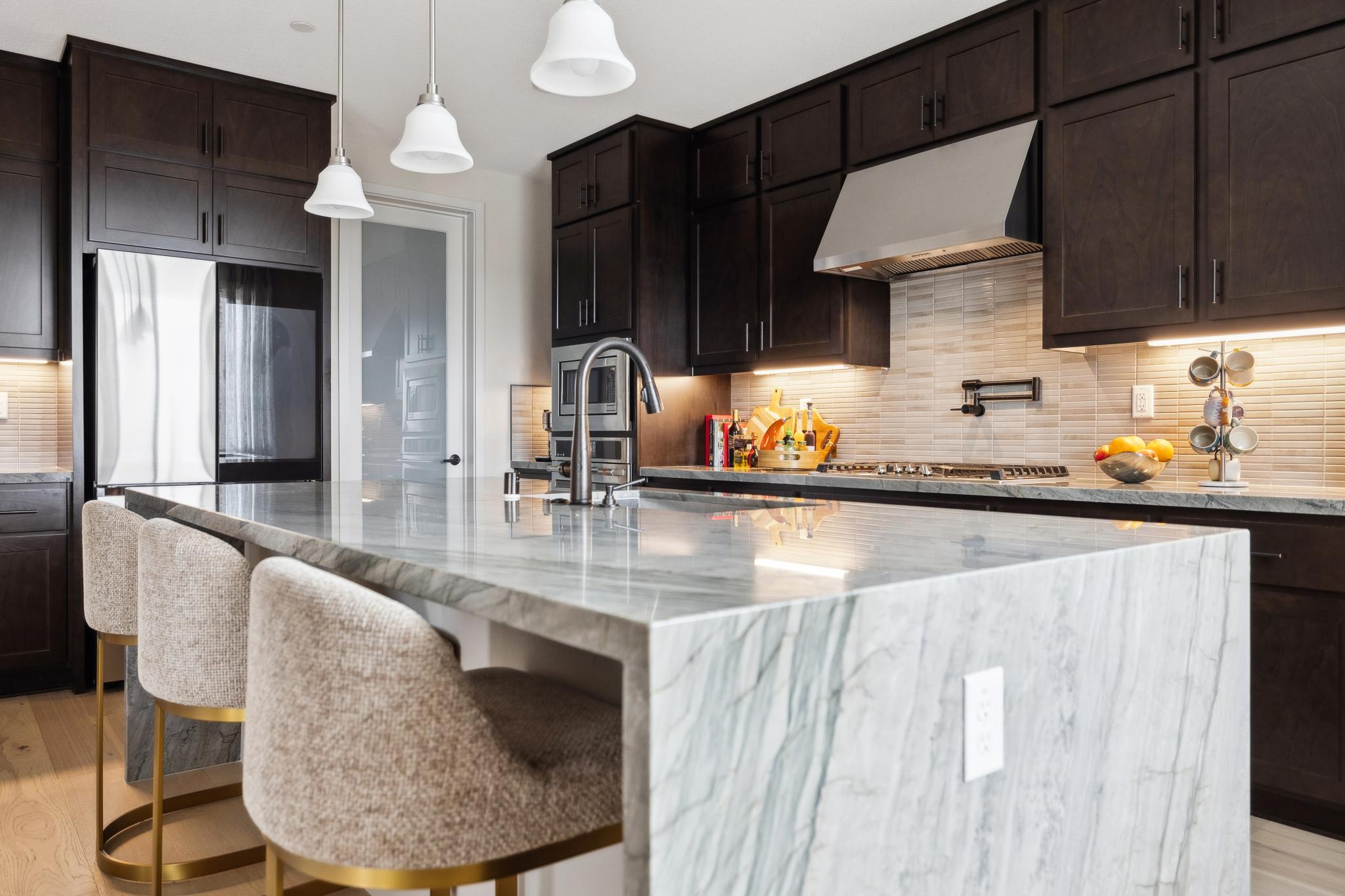Kitchen island and countertop surfaces with stainless appliances and tile backsplash