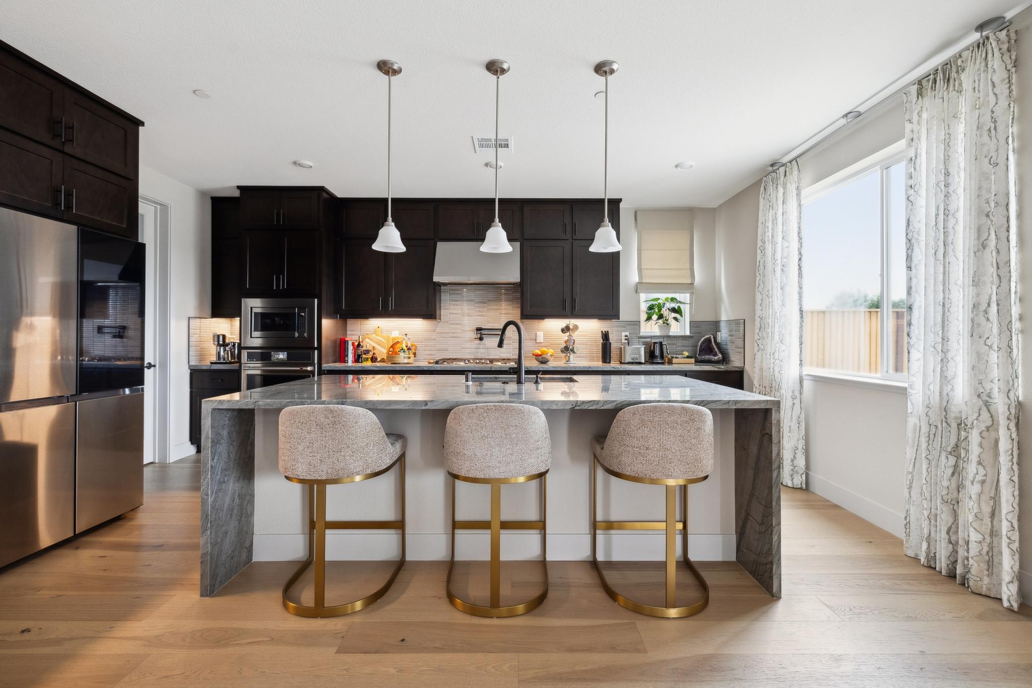 Renovated kitchen with dark cabinetry, island seating and pendant lighting