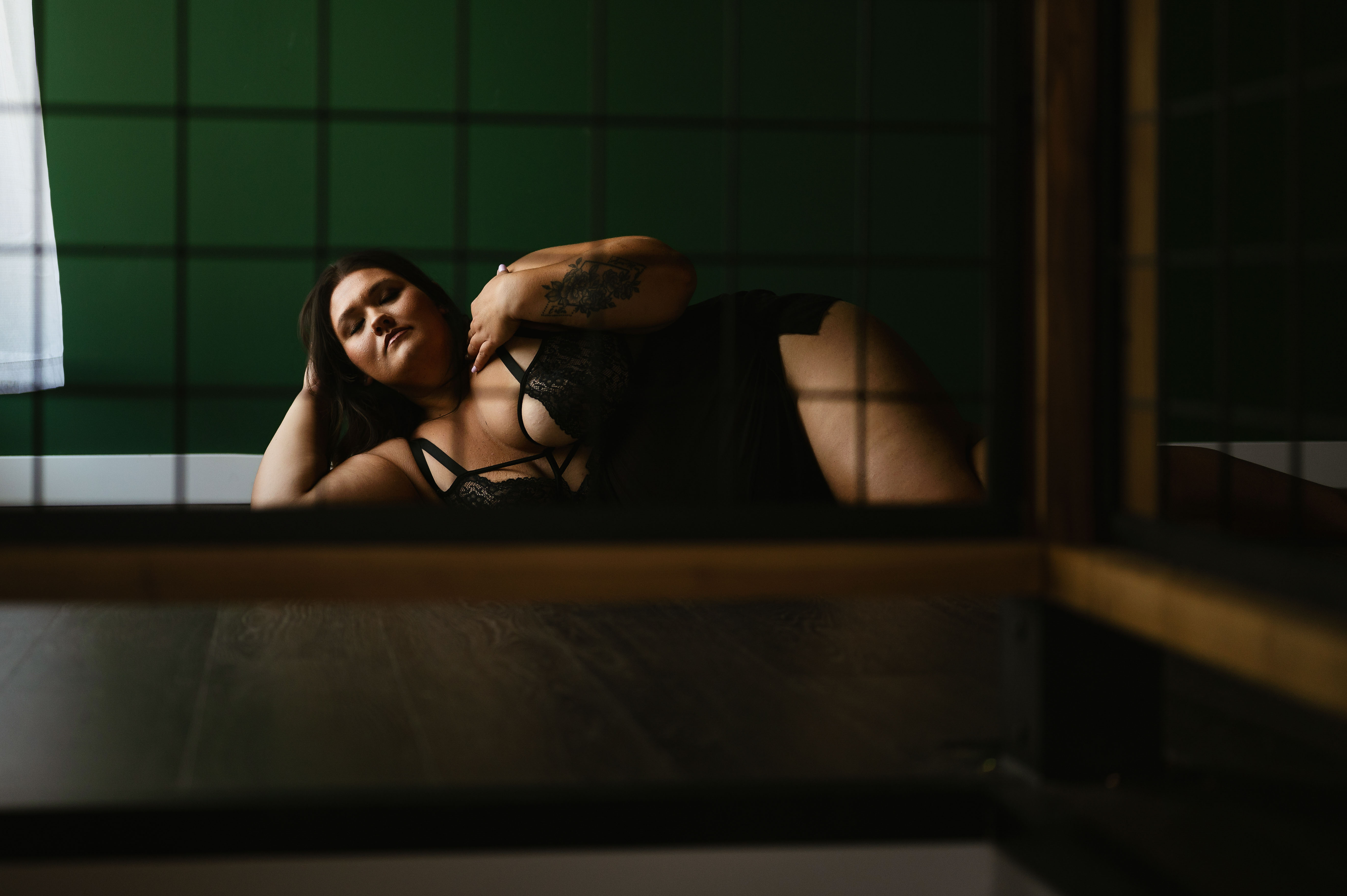 Artistic boudoir photography of a nude woman draped with white fabric, captured in dramatic lighting to highlight sensual feminine beauty.