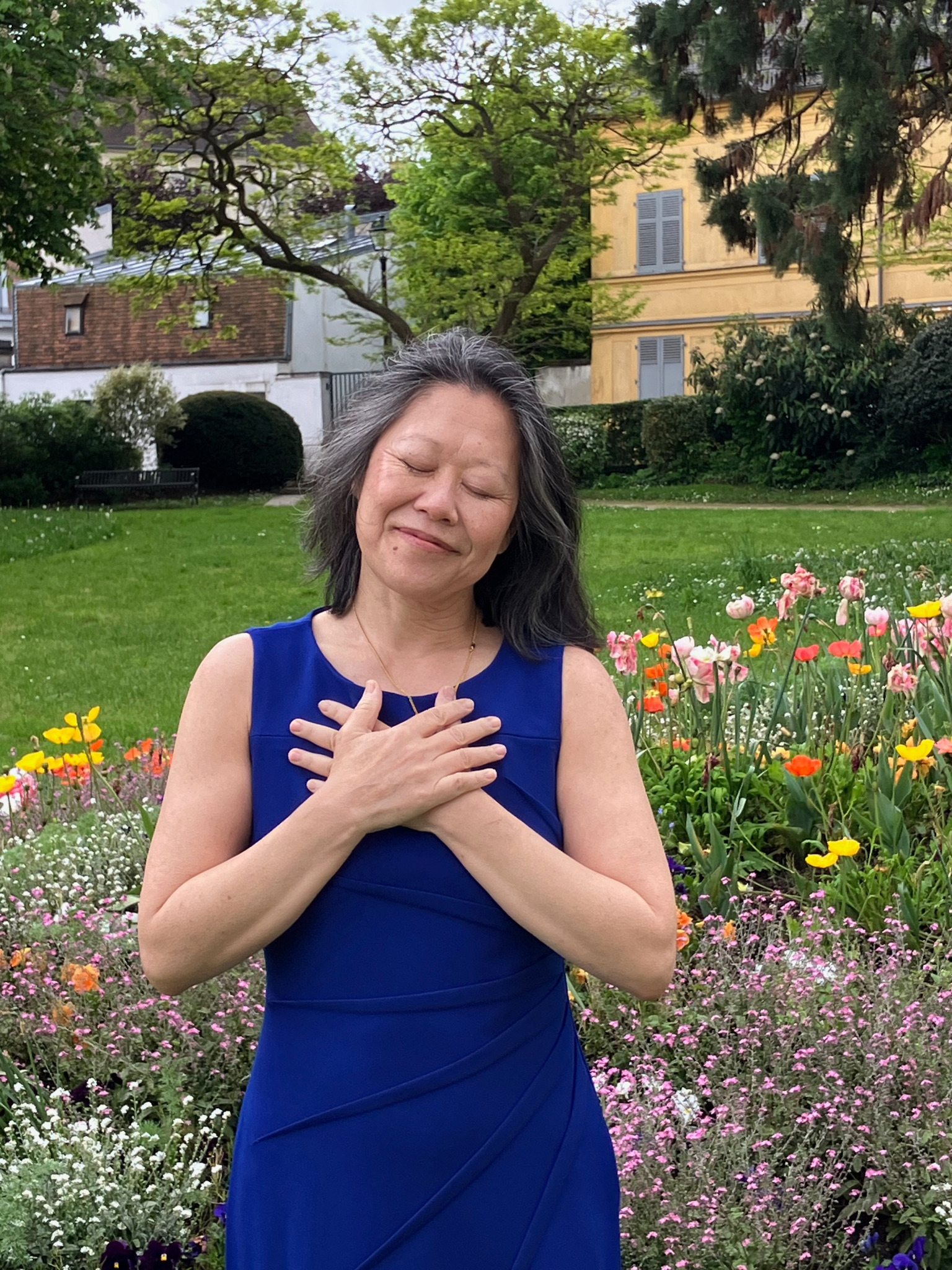Panda Hershey with hands on heart, eyes closed, at peace in a garden