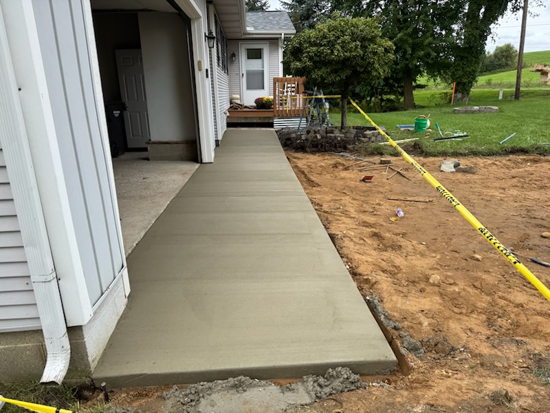 Fresh concrete slab running along the side of a house to the garage entry