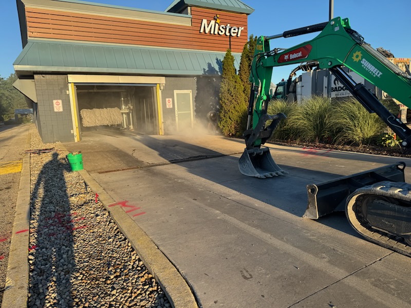 Excavator working on a commercial concrete project by Kelly’s Custom Concrete in Holland, MI.