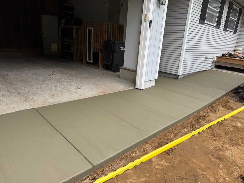 Freshly poured concrete walkway and driveway extension beside a home in Holland, MI.