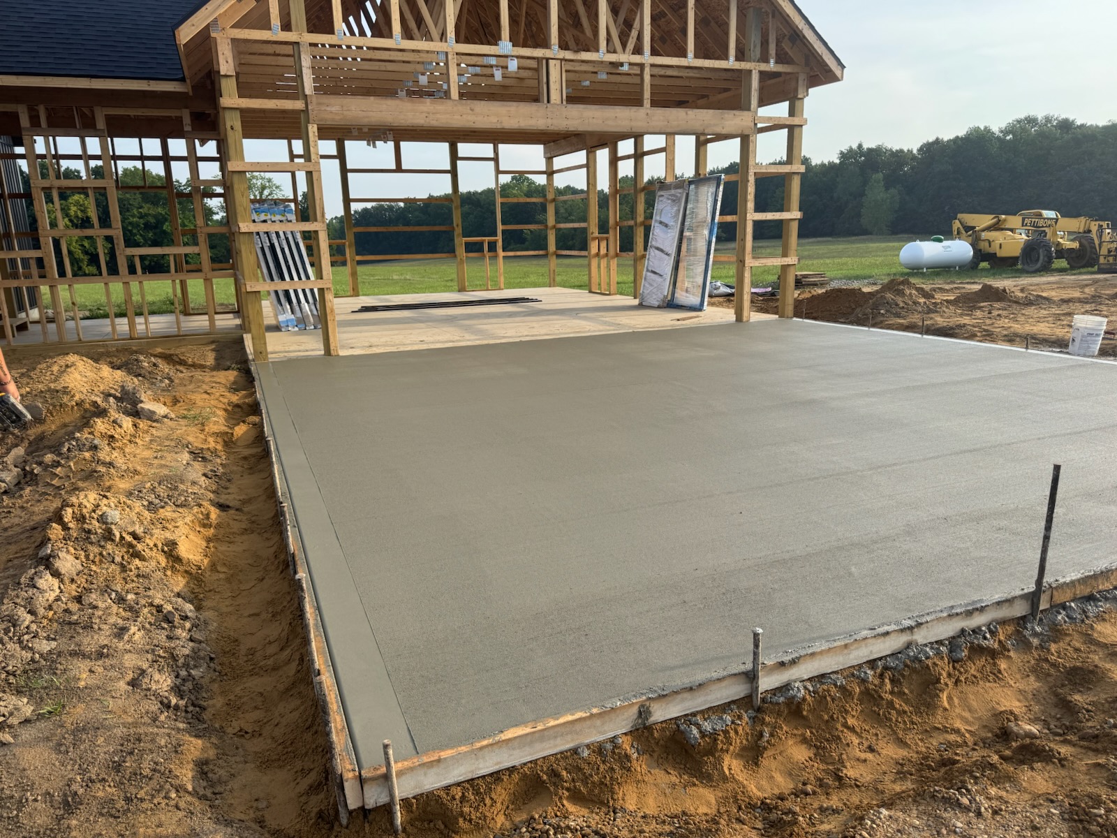 New concrete slab poured inside a timber-frame pole barn