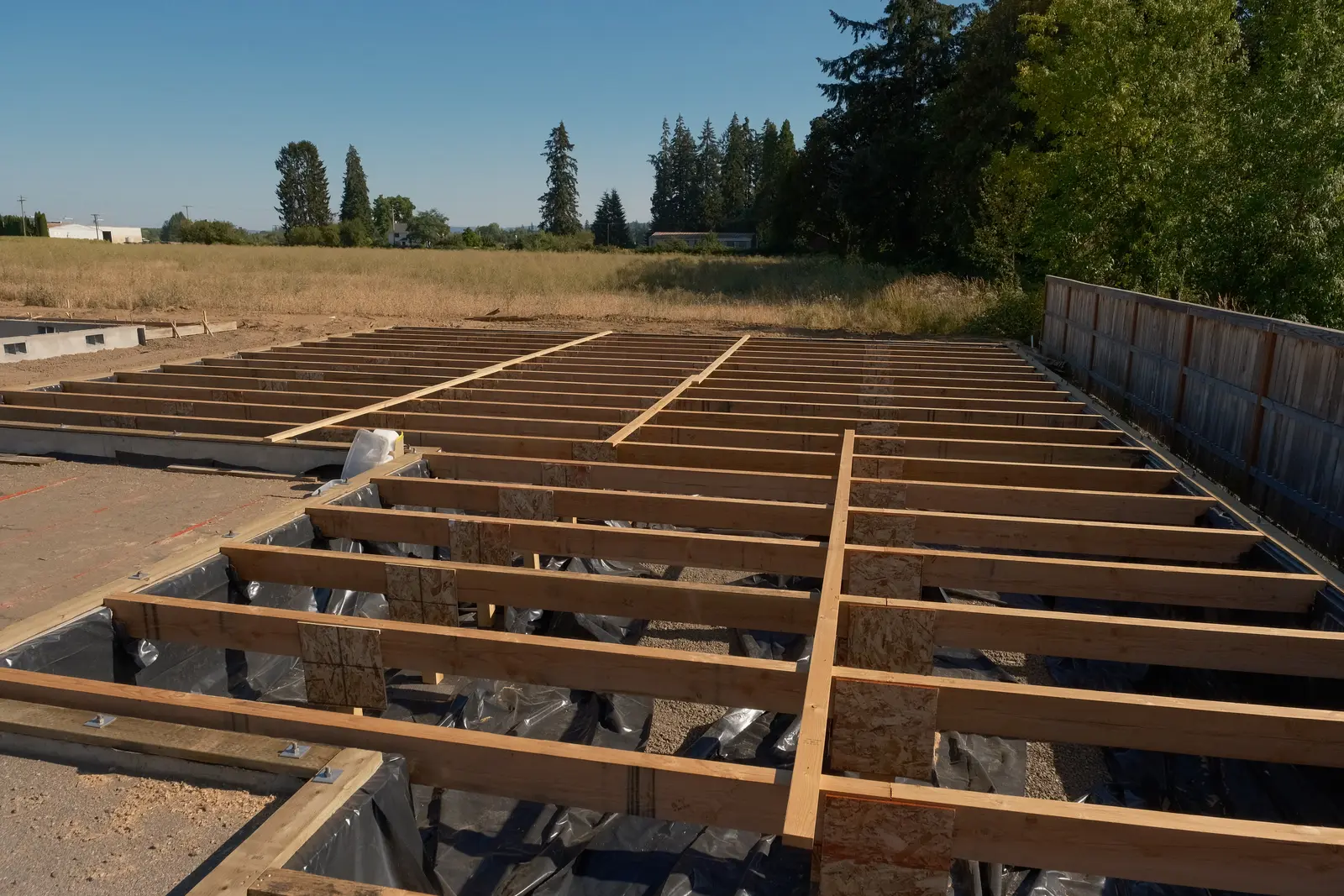Floor joists installed across a new residential foundation at a Holt Homes project