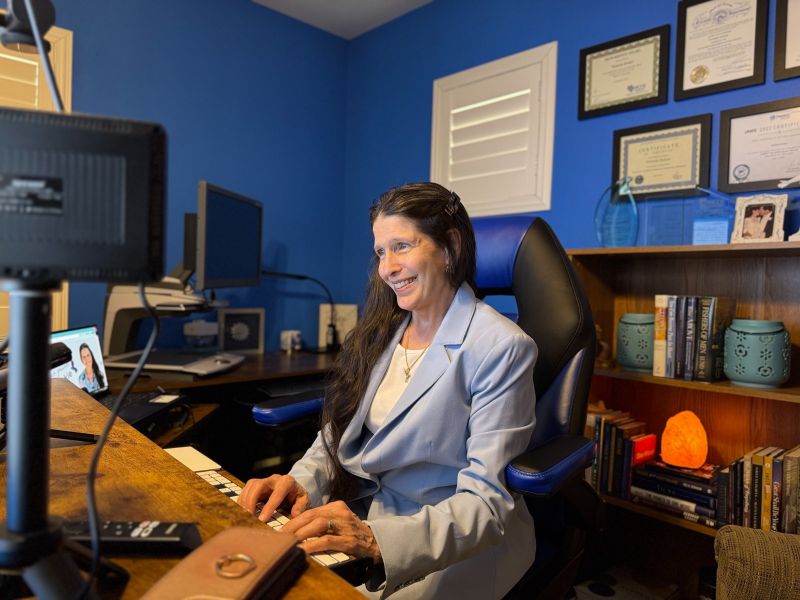Victoria Essner sits at her desk in her home office, working at her computer. She is surrounded by multiple monitors, assistive technology, books, and framed certificates displayed on the wall behind her. Victoria Essner sits at her desk in her home office, working at her computer. She is surrounded by multiple monitors, assistive technology, books, and framed certificates displayed on the wall behind her.