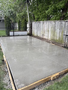 New concrete parking pad poured in a fenced Mississauga backyard