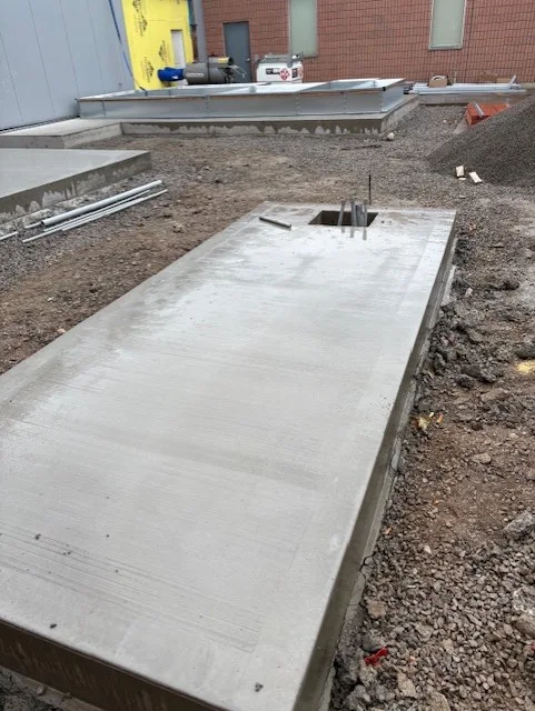 Reinforced concrete equipment pad poured beside a commercial building in Toronto