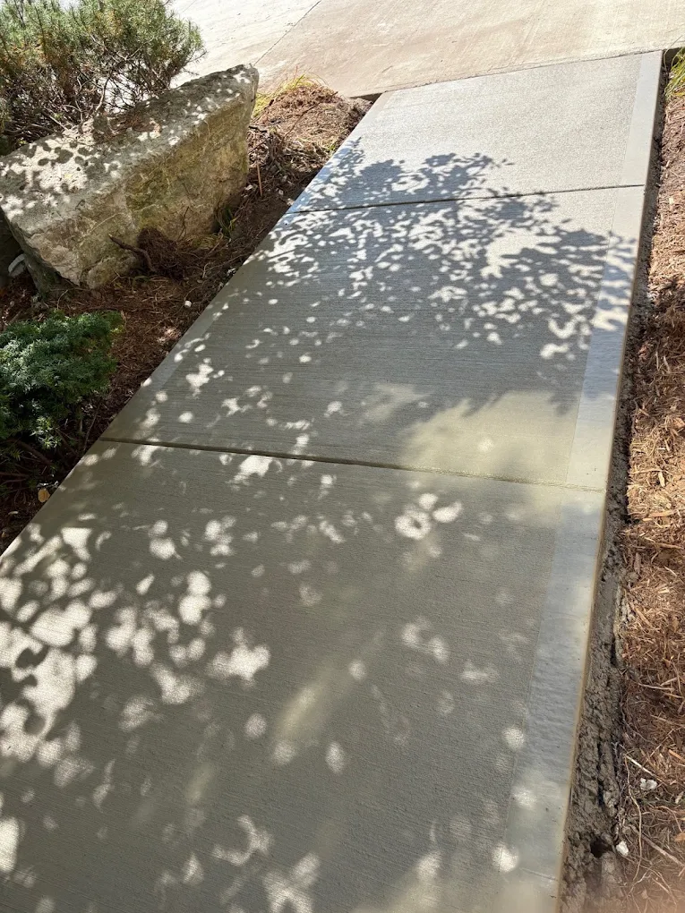 New broom finished concrete walkway beside a garden bed in Brampton