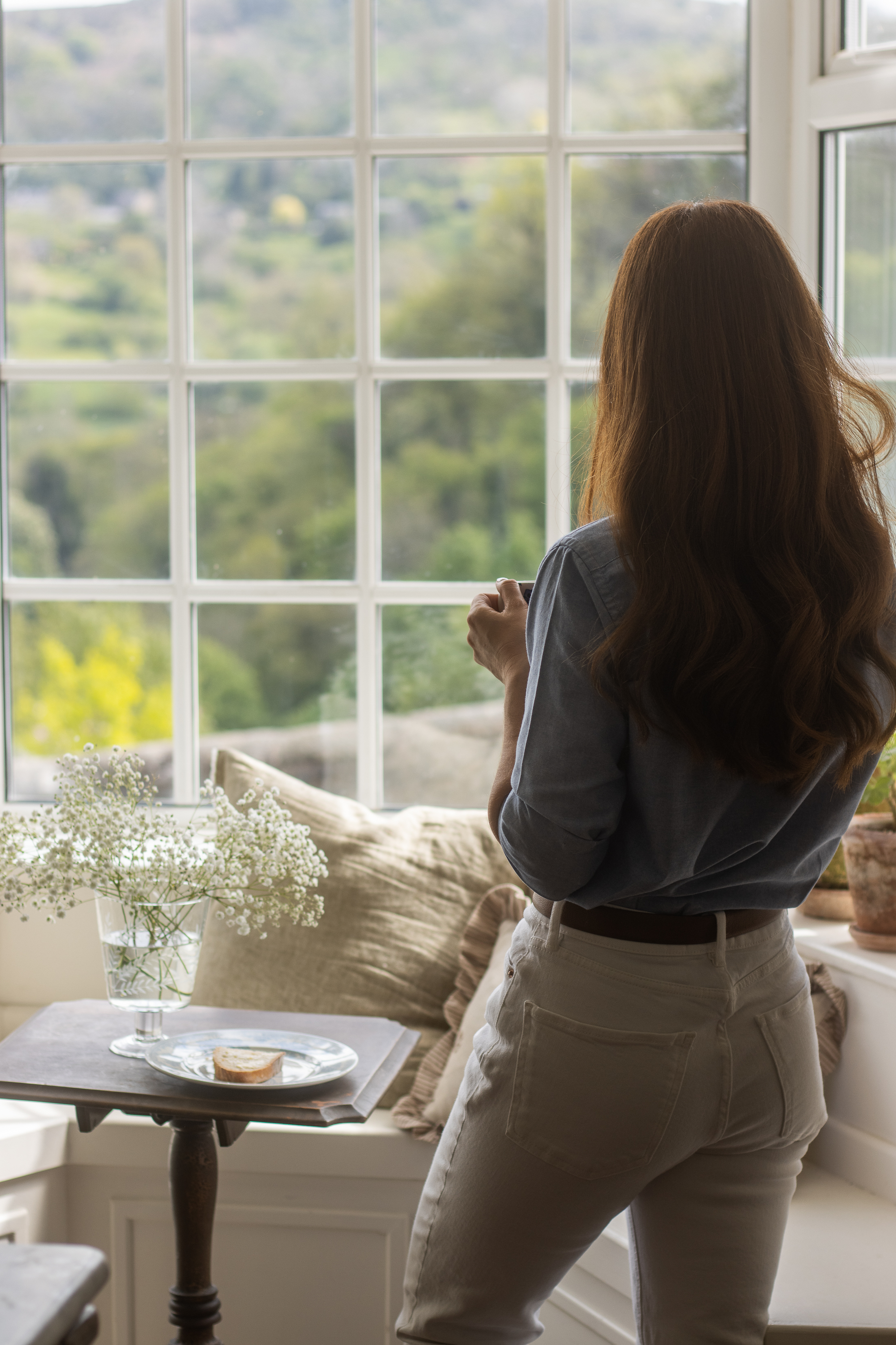 A woman standing beside a window and looking outside