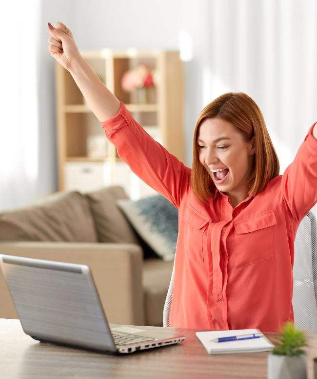 woman in red shirt excited while looking at laptop