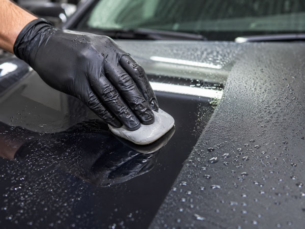 Clay bar paint decontamination on a car hood during a full exterior auto detail