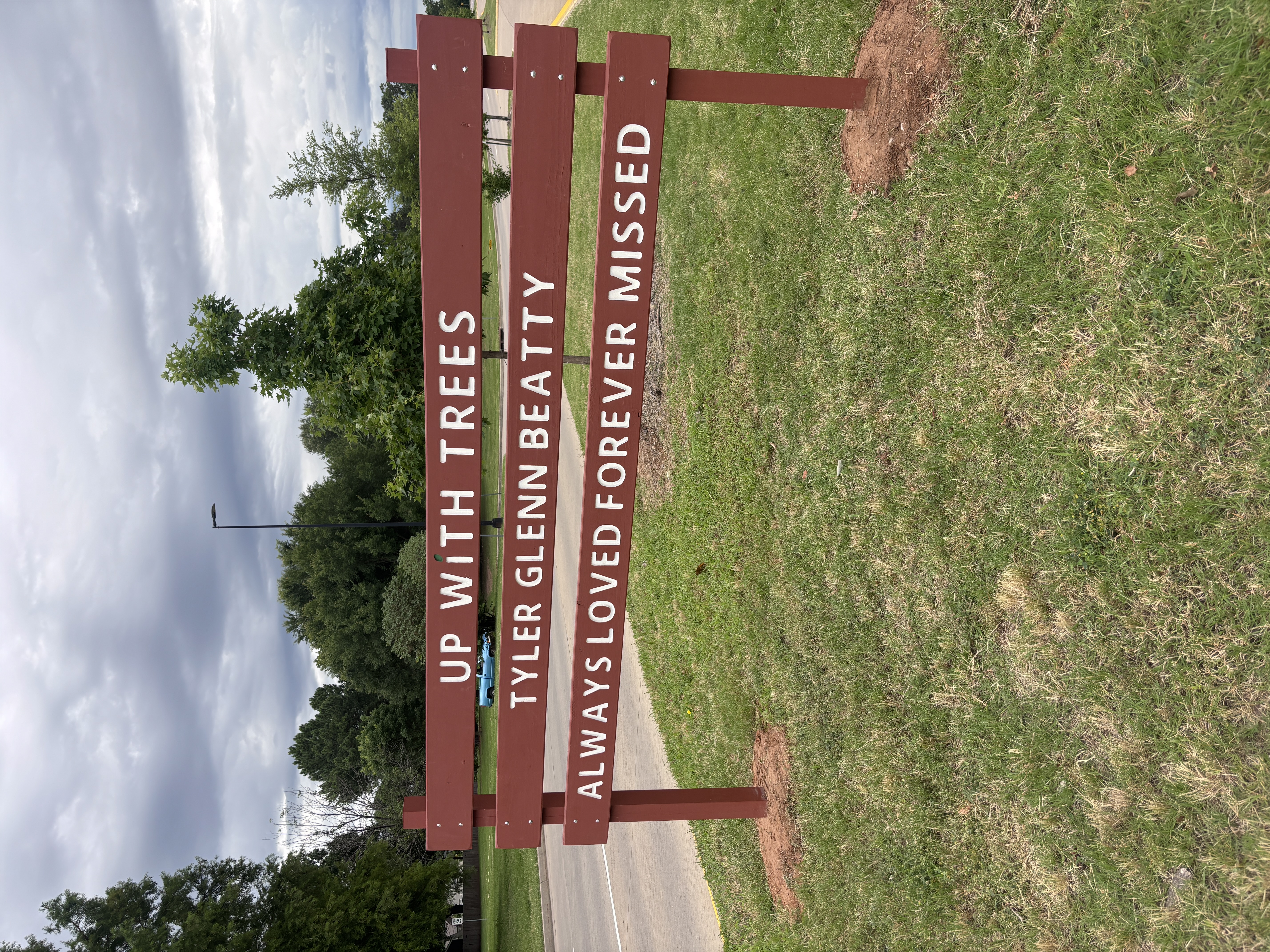 Jenn Mount and her father Darrell Beatty standing at the Tyler Glenn Beatty commemorative Up With Trees sign at 52nd Street and Riverside Drive in Midtown Tulsa on Father's Day