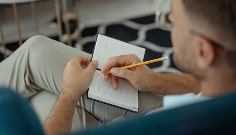 Man writing in a journal reflecting on his core identity values and faith Man writing in a journal reflecting on his core identity values and faith