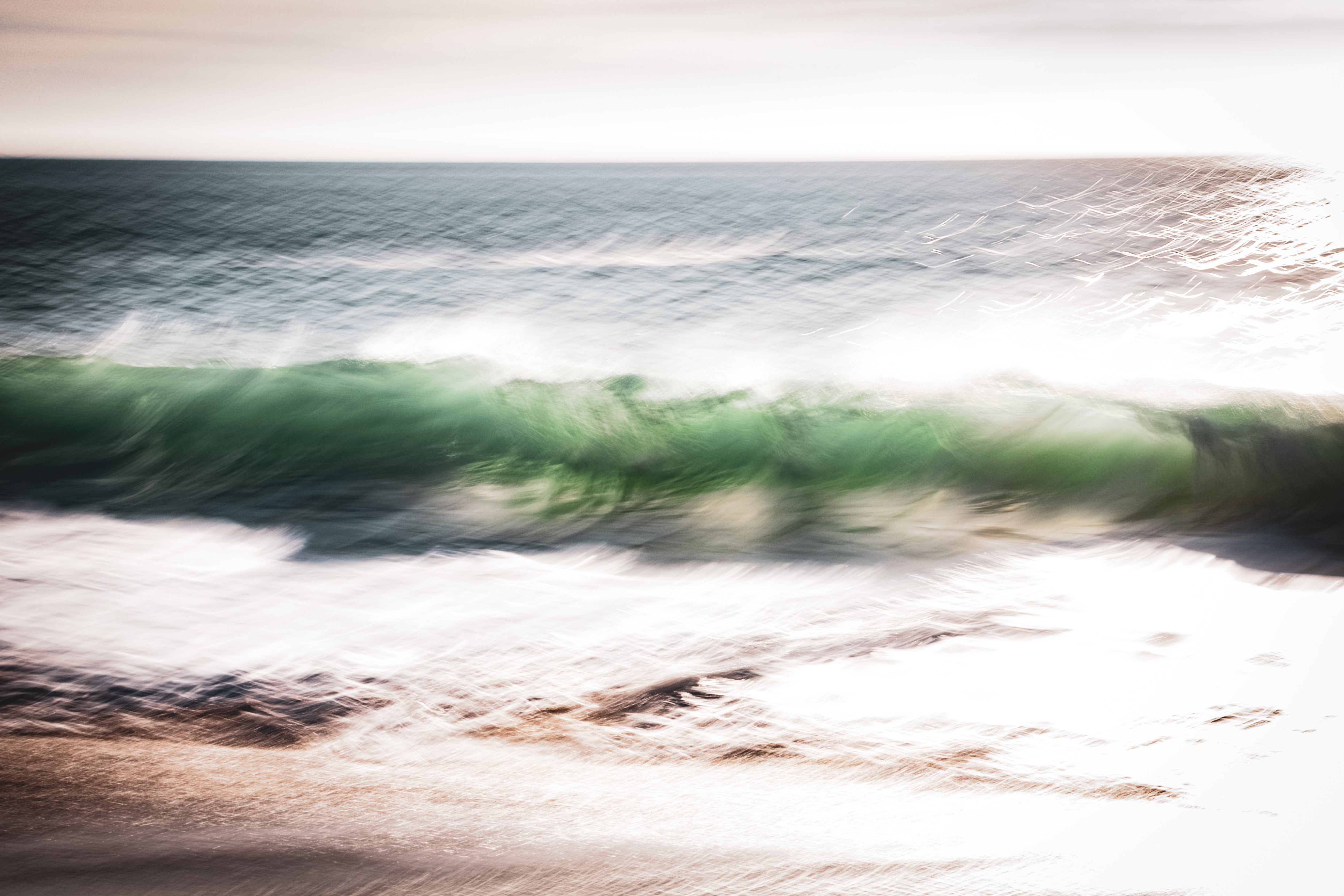 Long exposure ocean photograph of a breaking wave at Huntington Beach, California — soft green water in motion against a pale sky. Part of the Coastal Blur series by Angie Harker, captured during the last weekend with her mother.