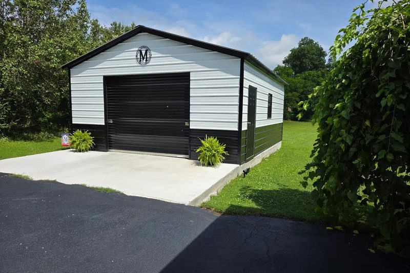 20 by 25 white and black metal garage with a single roll-up door on a concrete pad