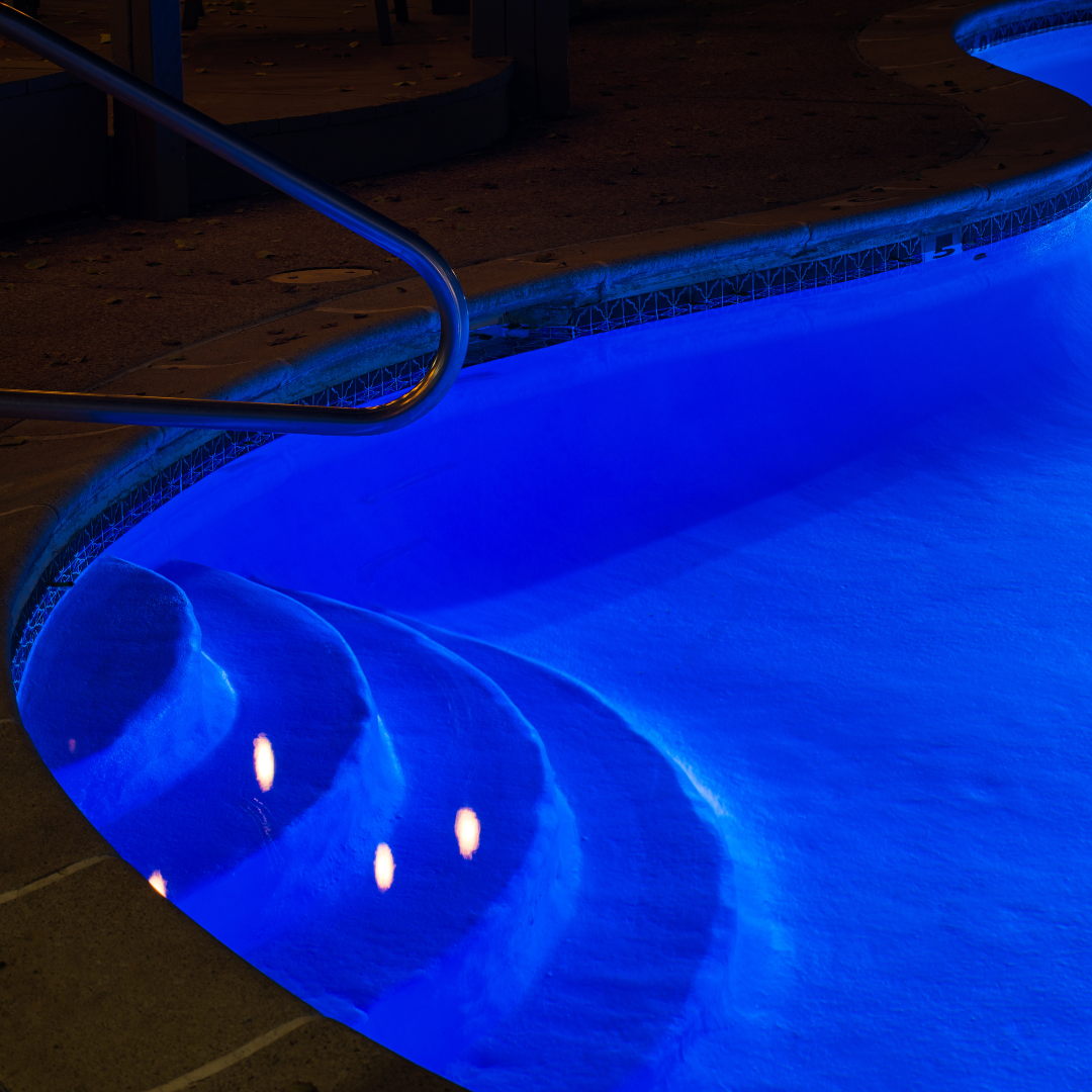Swimming pool illuminated by blue underwater lights at night