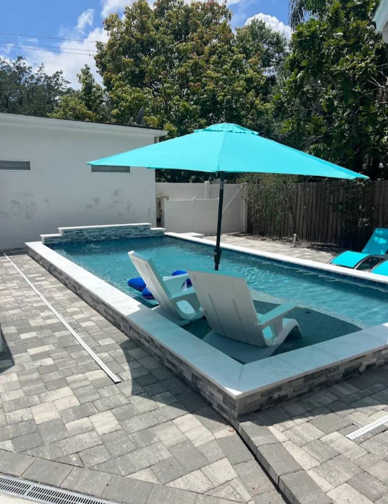 Compact swimming pool with lounge chairs and a turquoise umbrella