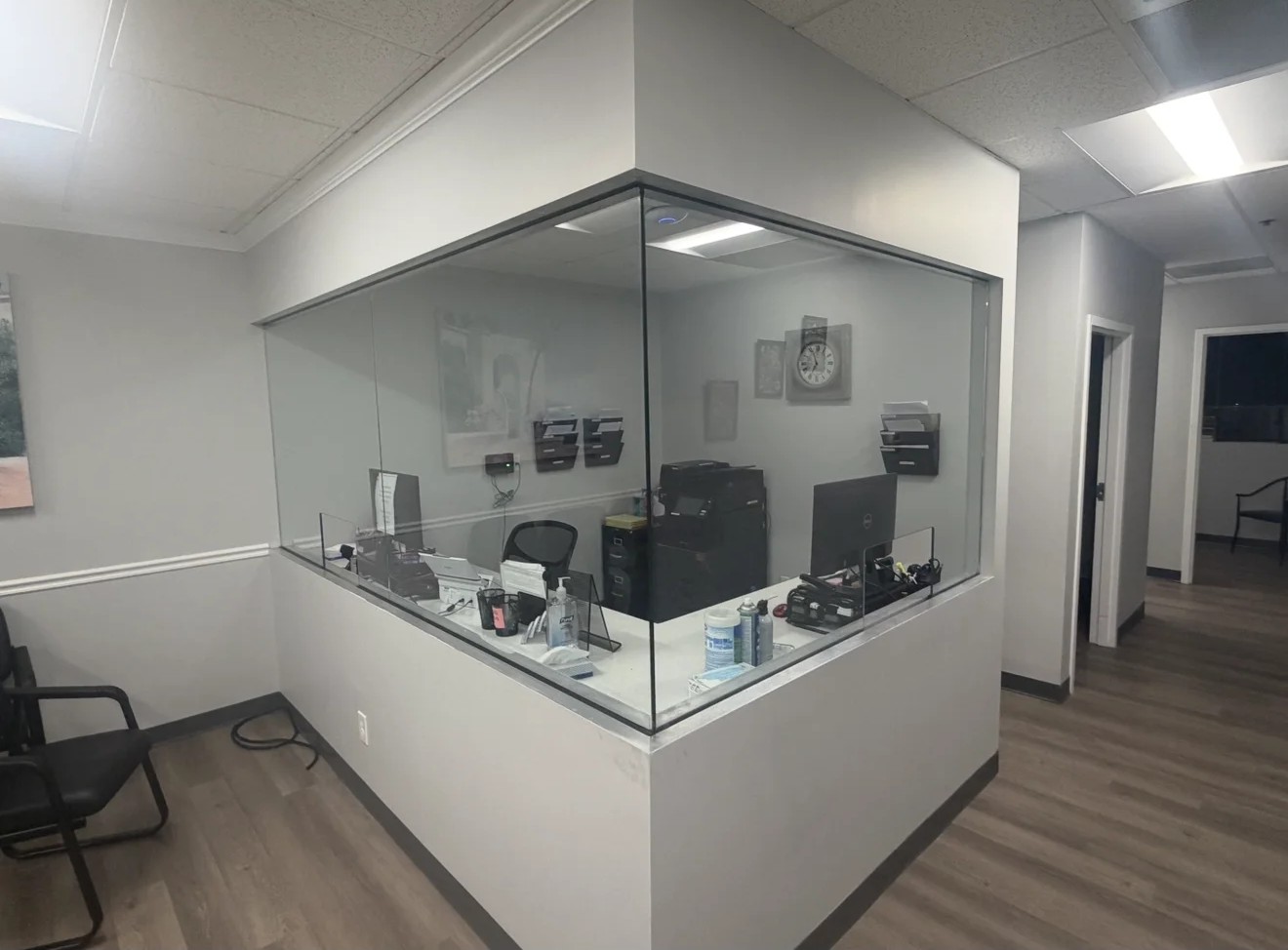 Commercial office glass partition installation with reception counter and two office chairs