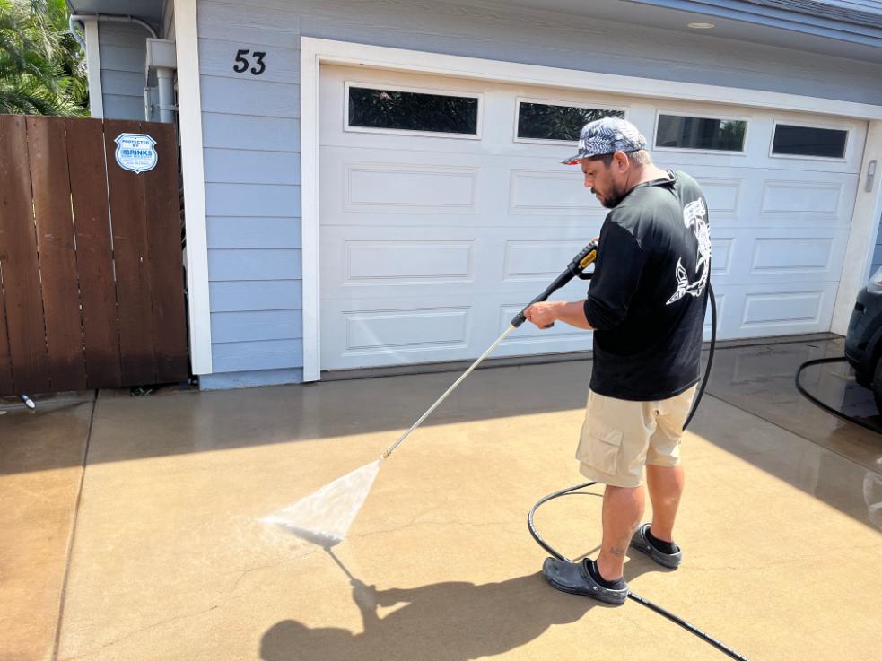 CSI worker power washing concrete driveway with precision, demonstrating thoroughness and pride in delivering spotless results.