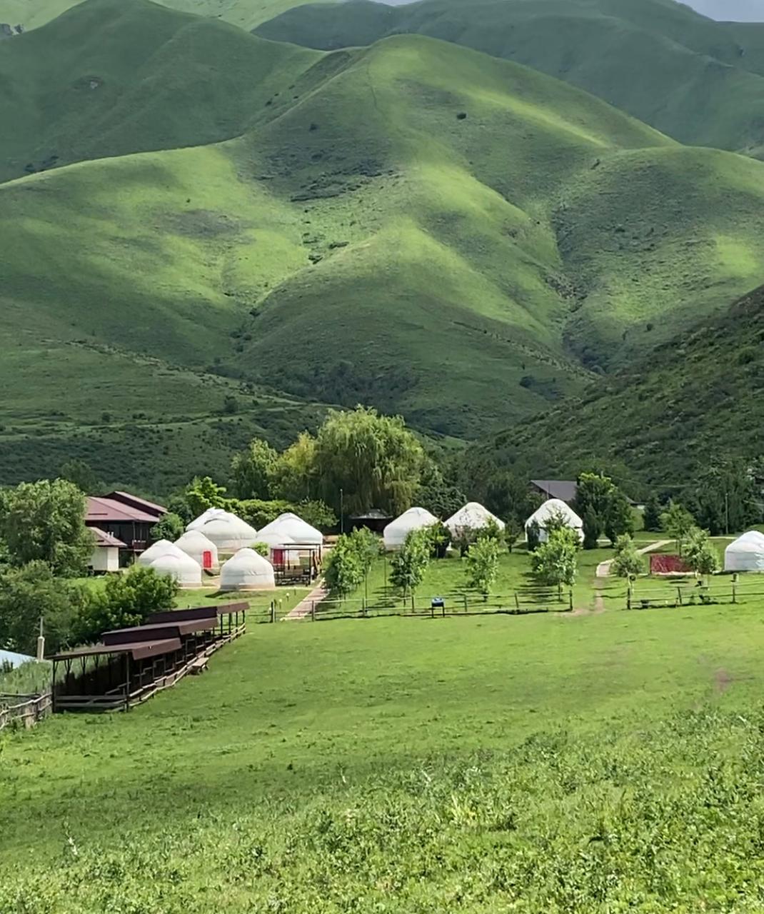Paisaje de primavera en las montañas cerca de Almaty, Kazajistán, con colinas verdes y campamento de yurtas