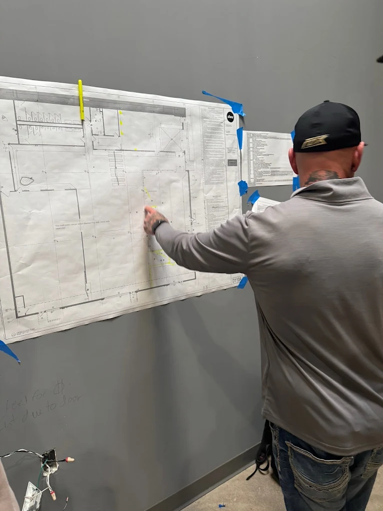 Jason pointing at a project layout blueprint, highlighting operational precision