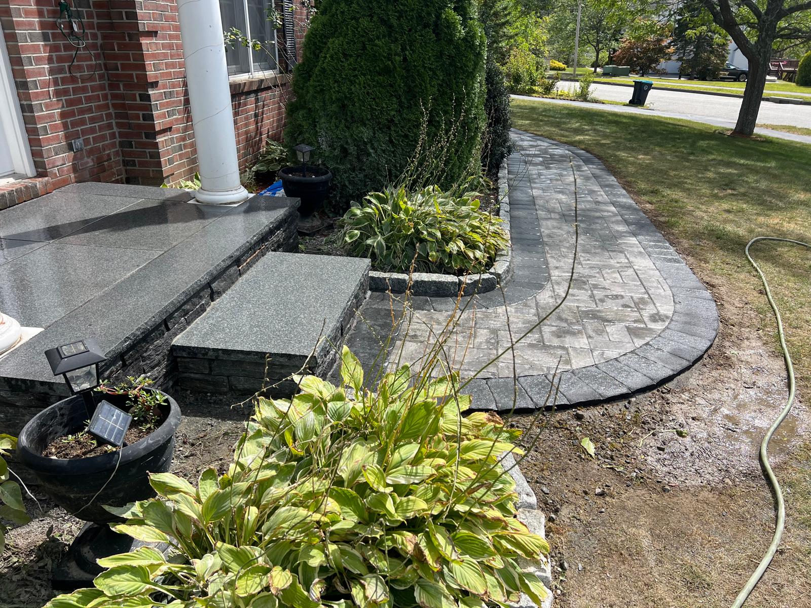 Team of skilled landscapers installing a custom stone retaining wall in a residential backyard, using high-quality materials and precise techniques.
